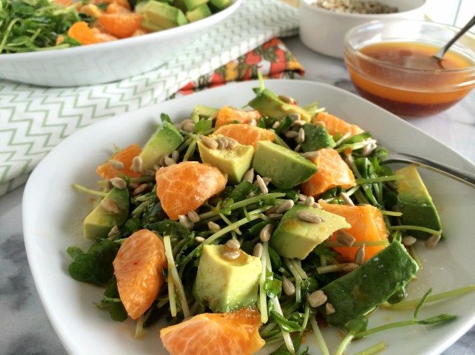 Pea shoots, oranges, and avocados with orange-chili vinaigrette on plate